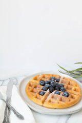 Belgian Waffle with Blueberries and Maple Syrup, Dusted with Powdered Sugar, Flay Lay on Marble Background, Copy Space