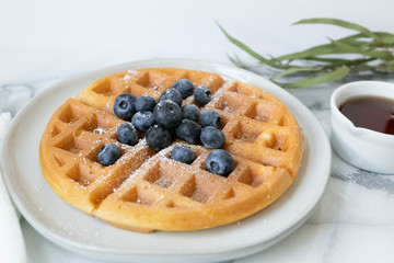 Belgian Waffle with Blueberries and Maple Syrup, Dusted with Powdered Sugar, Flay Lay on Marble Background, Copy Space