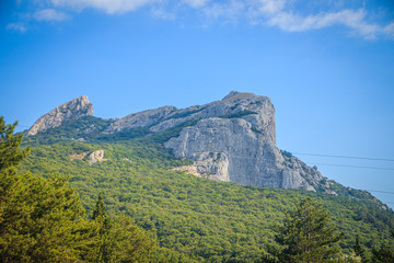 Russian mountains. Crimea. Summer mountains background. Forest and mountains in the sun on the background of a cloudy sky above the peninsula of Crimea. Sunny, bright, saturated raster photo