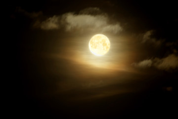 Full moon in clouds on black sky background