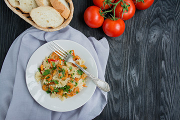 Italian pasta in a sauce with shrimps on a plate, top view. Dark wooden background. Space for text.