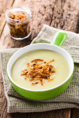 Fresh homemade cream of potato soup in green bowl garnished with crispy onion strings (Selective Focus, Focus on the onion strings in the front)