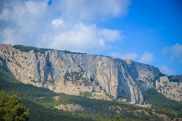 Fototapeta premium Russian mountains. Crimea. Summer mountains background. Forest and mountains in the sun on the background of a cloudy sky above the peninsula of Crimea. Sunny, bright, saturated raster photo