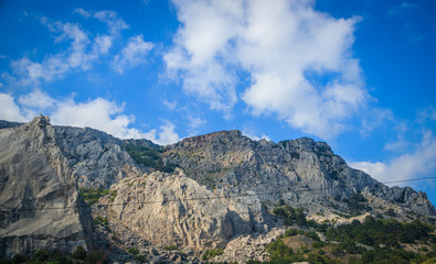 Fototapeta premium Russian mountains. Crimea. Summer mountains background. Forest and mountains in the sun on the background of a cloudy sky above the peninsula of Crimea. Sunny, bright, saturated raster photo