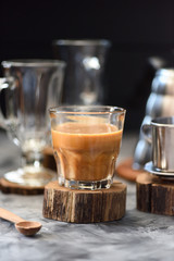 Vietnamese drip coffee with coconut milk in glass on wood slab on dark background