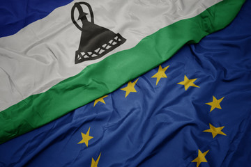 waving colorful flag of european union and flag of lesotho.