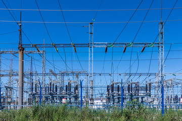 The poles and wires of elecric substation on the background of blue sky in the sunny summer weather