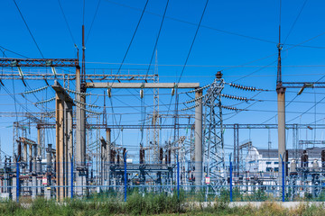 The poles and wires of elecric substation on the background of blue sky in the sunny summer weather