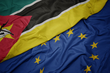 waving colorful flag of european union and flag of mozambique.