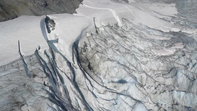Aerial Right/Pan Up: Shadow Of Helicopter On Bumpy, Snowy Valley At Bottom Of Rocky Mountains - Mendenhall Glacier, Alaska