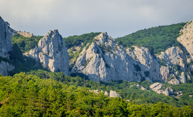 Russian mountains. Crimea. Summer mountains background. Forest and mountains in the sun on the background of a cloudy sky above the peninsula of Crimea. Sunny, bright, saturated raster photo