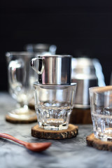 Making drip coffee Vietnamese style. Metal coffee maker phin on glass ready for pouring coffee on dark background copy space