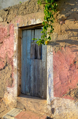 Worn Blue Wooden Door Against a Textured Pink Wall