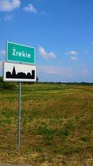 Znak drogowy w Europie na tle nieba i łąk z drzewami