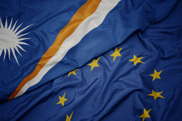 waving colorful flag of european union and flag of Marshall Islands .