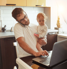 Father Working From Home On Laptop With Baby daughter