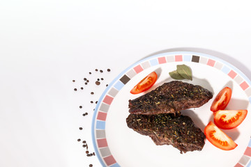 grilled beef steak with vegetables on plate. Slices of juicy fresh meat with tomatoes and bay leaf on a white plate. Flat Lay and copy space