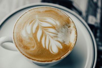 beautiful cappuccino coffee in a cup with a pattern on a foam in the form of twigs