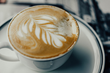 beautiful cappuccino coffee in a cup with a pattern on a foam in the form of twigs
