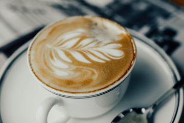 beautiful cappuccino coffee in a cup with a pattern on a foam in the form of twigs
