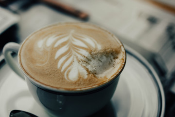 beautiful cappuccino coffee in a cup with a pattern on a foam in the form of twigs