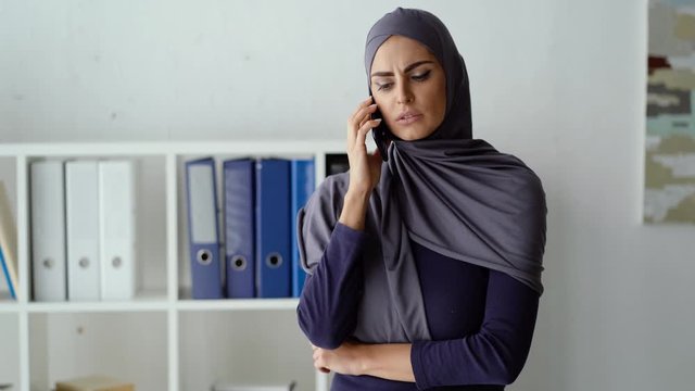 Muslim woman having an unpleasant conversation with her boss on the phone. She's being scolded for incompetence or failure.