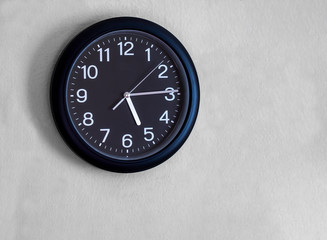 Fototapeta na wymiar Black round wall watch is show quarter past five o'clock.