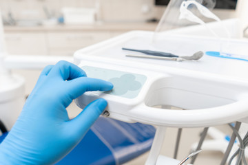 The hand of the dentist in the glove presses the control buttons of the chair.. Dental work in clinic. Operation, tooth replacement. Medicine, health, stomatology concept.