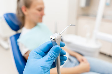 Close-up hand of dentist in the glove holds Gun dental water and air. The patient in blue chair at...