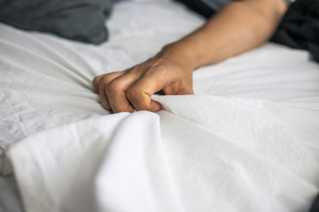 Close up detail of a women’s hand grabbing on to the bed sheets, intimacy, love, erotic concept