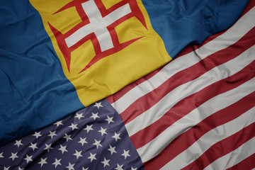 waving colorful flag of united states of america and national flag of madeira. macro