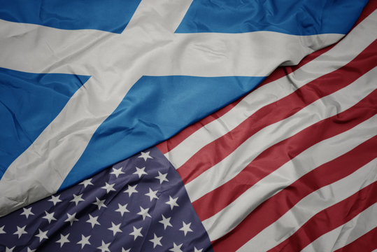 waving colorful flag of united states of america and national flag of scotland. macro