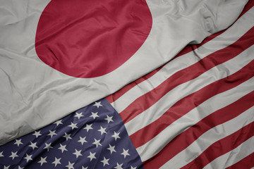 waving colorful flag of united states of america and national flag of japan.