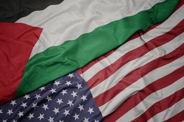 waving colorful flag of united states of america and national flag of palestine.