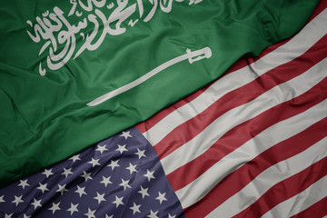 waving colorful flag of united states of america and national flag of saudi arabia.