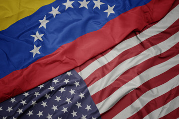 waving colorful flag of united states of america and national flag of venezuela.