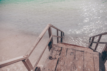 Old wooden staircase descends straight to the ocean on the tropical island