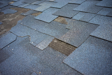 Сlose up view of bitumen shingles roof damage that needs repair. © cherokee4