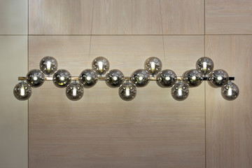 Lighting balls on the chandelier in the lamplight, light bulbs hanging from the long rail, silver pendant lamps on the light background