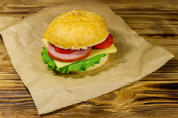 Fresh delicious homemade cheeseburger on brown paper on wooden table