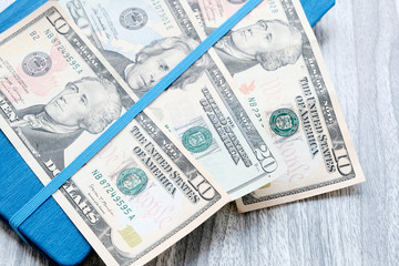 Dollars on a blue notebook. American banknotes of different denominations . Wooden marble Board background. The problem of budgeting, calculation of estimates. The concept of profitable investment.