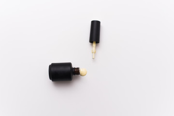 yellow gel nail polish in a black bottle on a white background. Manicure concept for blogs and design templates