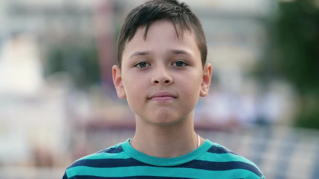 Happy brunet boy standing and smiling cheerily on Dnipro embankment in slo-mo 