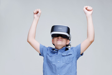Young happy boy in glasses of virtual reality on gray background. Augmented reality, game, future technology concept. VR.