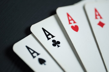 Four aces on lie on a black wooden background.