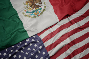 waving colorful flag of united states of america and national flag of mexico.