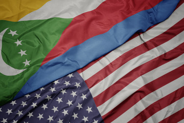 waving colorful flag of united states of america and national flag of comoros.