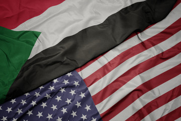Obraz premium waving colorful flag of united states of america and national flag of sudan.