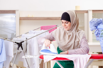 Woman in hijab doing clothing ironing at home
