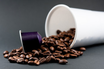 Plastic cup of white coffee lying, across a black background, with brown coffee beans inside the glass. Cafeteria and food.